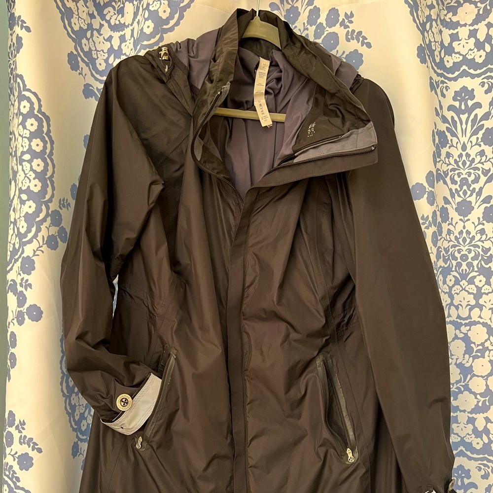 This is a women’s black, lined, midi raincoat size 12. It has a high-low hem
